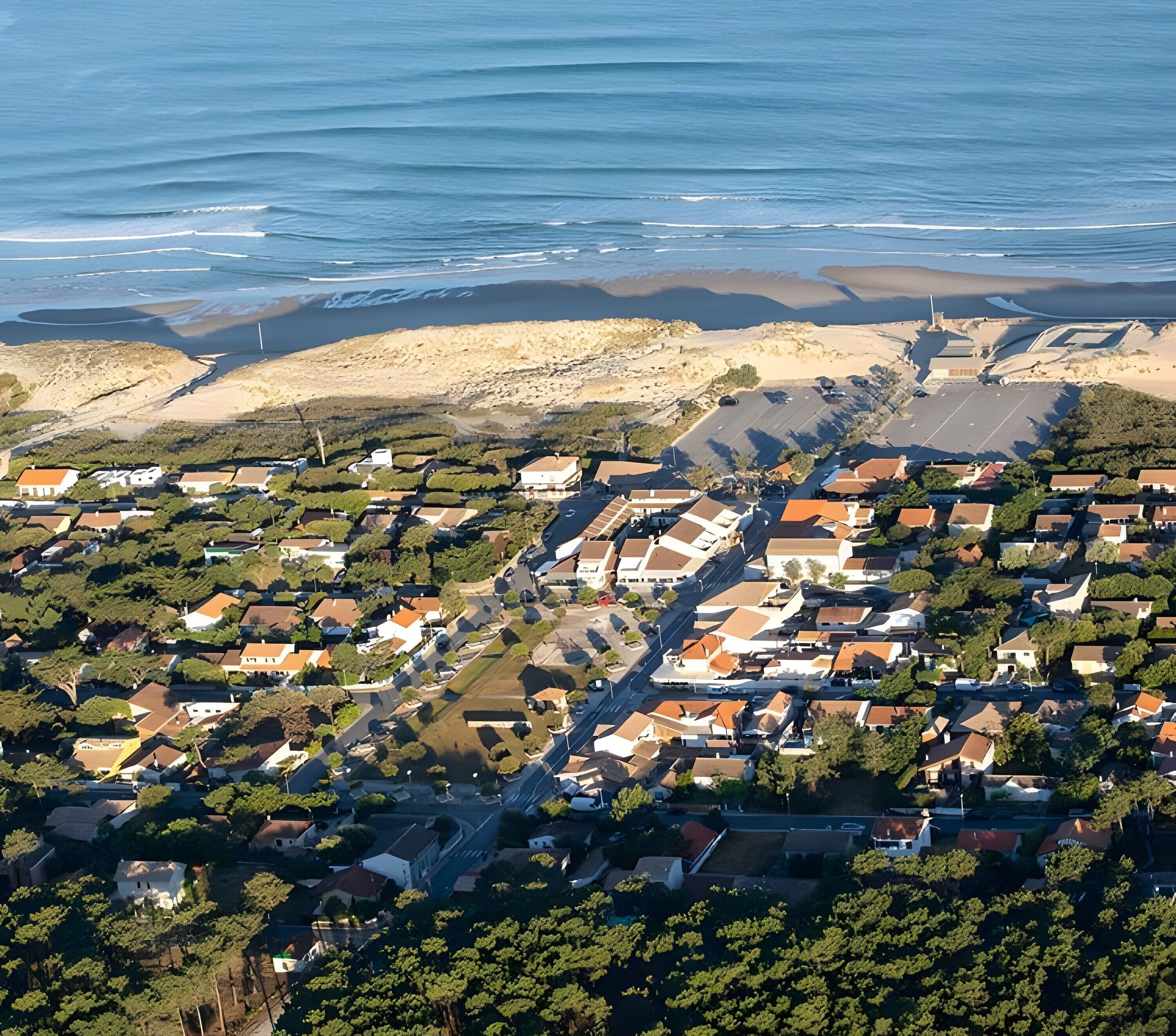 Luftaufnahme einer Küstenwohngegend mit Häusern, Straßen und einem Strand.