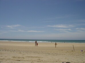 Una playa con cielo despejado, orilla arenosa e huellas.