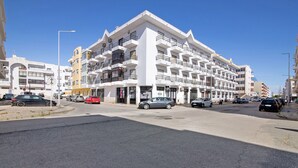 A multi-story hotel with balconies, a parking lot, and a clear blue sky. - Apartamento Mar Olhão | Spacious 2-Bedroom Apartment in Prime Location (Olhão)