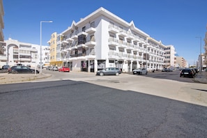 A multi-story hotel with balconies, a parking lot, and a clear blue sky. - Apartamento Mar Olhao – Moderno e Confortável no Centro de Olhão (Olhão)