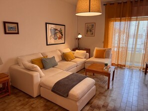 A living room with a sofa, armchairs, a coffee table, and a lamp.