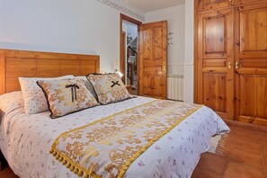 Ein Schlafzimmer mit einem hölzernen Kopfteil, einer blumigen Tagesdecke und einem großen Holzschrank.