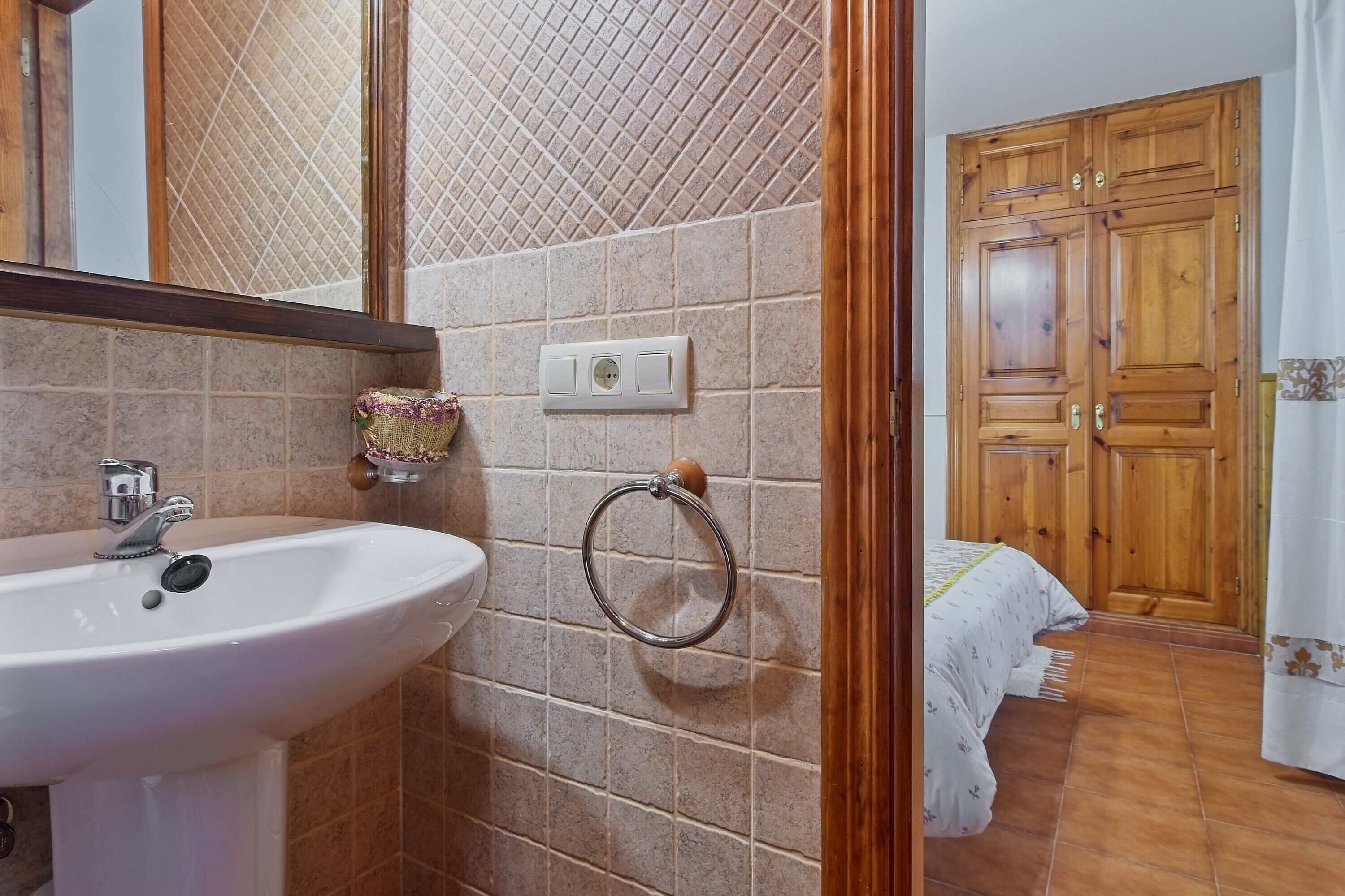 Een badkamer met een wastafel, spiegel en handdoekhouder.