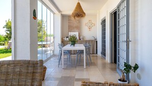 A spacious patio with a dining table, chairs, and a hanging light fixture.