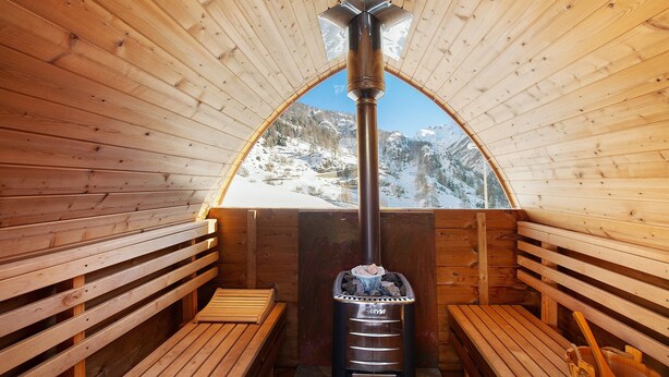 A wooden sauna with benches, a central fire feature, and a view of a snowy mountain. - Apartment 'La Cachette' with Mountain View, Private Terrace and Wi-Fi (Aosta)