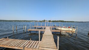 A wooden dock extending into a calm lake with a boat docked at the end. - Cottage #4 - Beautiful 3 Bedroom Lakefront Cottage - Fully Renovated in 2024! (Ashville)