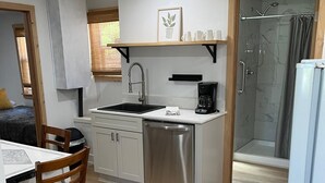 A compact kitchen with a sink, coffee maker, and a built-in shower. - Cottage #4 - Beautiful 3 Bedroom Lakefront Cottage - Fully Renovated in 2024! (Ashville)