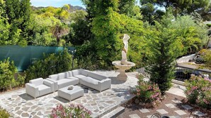 Un espace patio aménagé avec du mobilier d’extérieur, une fontaine décorative et diverses plantes.