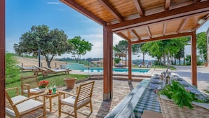 Un espace extérieur abrité comprenant une piscine, des chaises longues et une table dressée pour les repas.