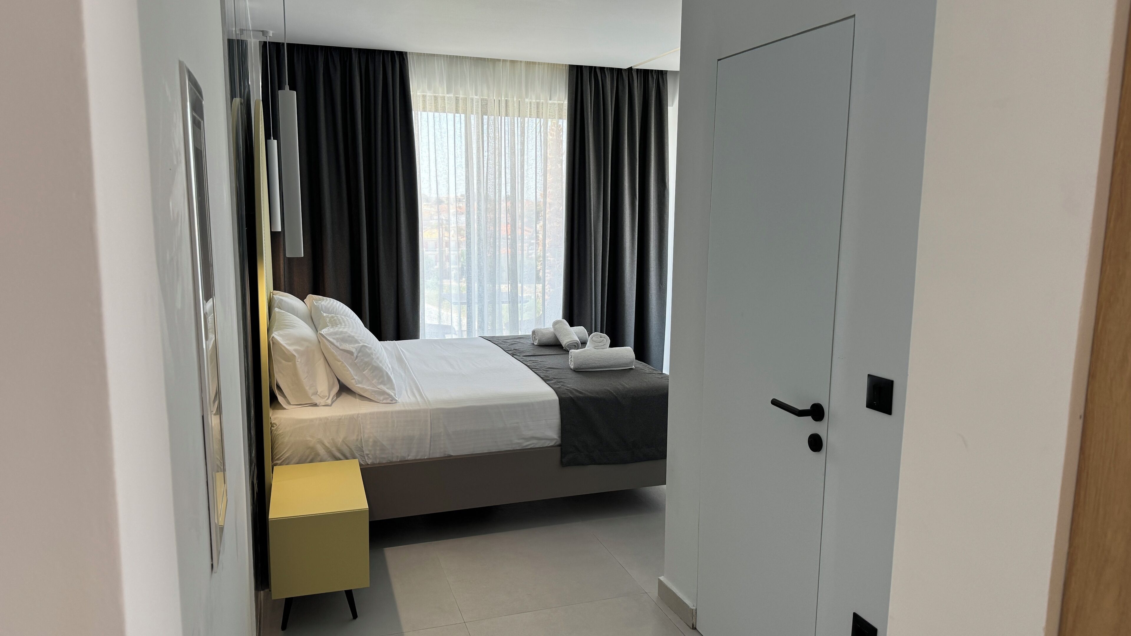 A modern bedroom with a bed, a bedside table, and a door.