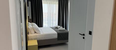 A modern bedroom with a bed, a bedside table, and a door.