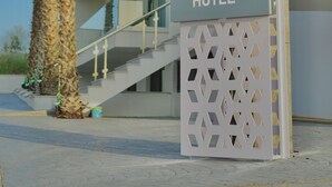 Un letrero moderno de hotel con el nombre "MONO ALEX HOTEL" y un panel decorativo.