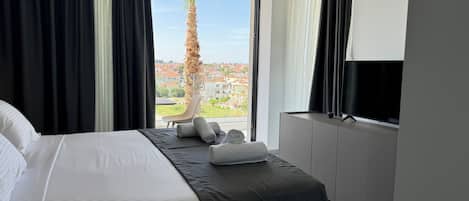 A hotel room with a bed, a TV, and a view of a cityscape.