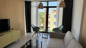 Una sala de estar moderna con un sofá, dos sillones, un televisor y una mesa de centro.