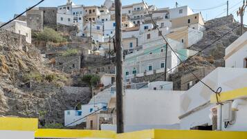 A hillside village with white buildings, a stone wall, and a yellow building in the foreground.