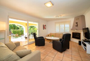 Un salon comprenant un canapé, deux fauteuils, une table basse, une cheminée et un téléviseur.