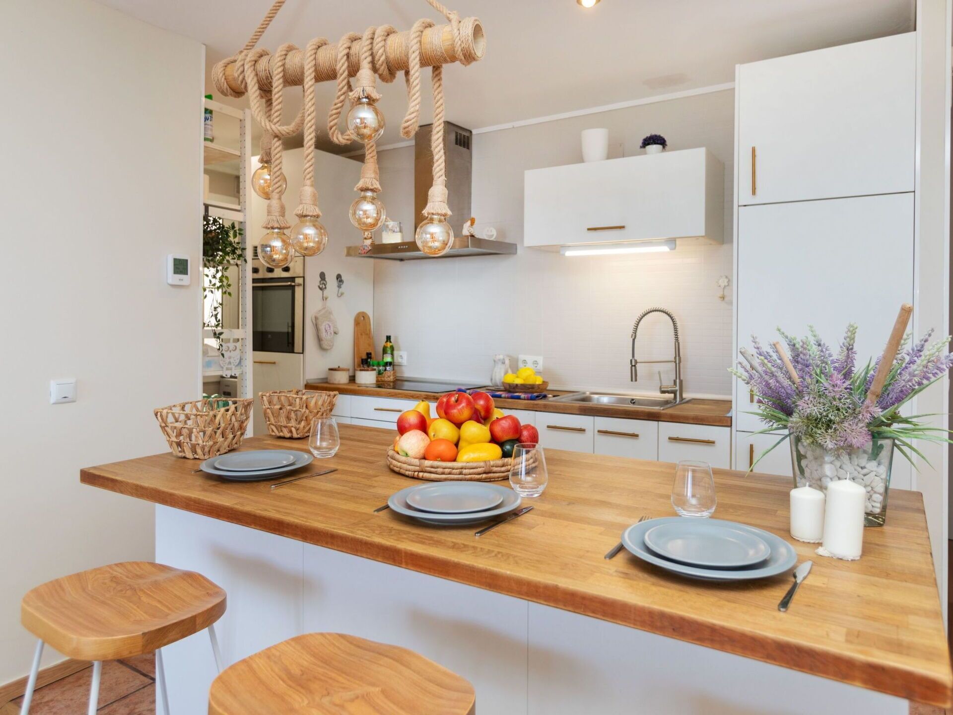 Una cocina moderna con una isla de madera, lámparas colgantes y un frutero.