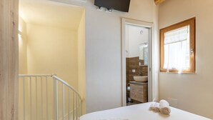 Ein Schlafzimmer mit Bett, ein Badezimmer mit Waschbecken und eine Treppe.