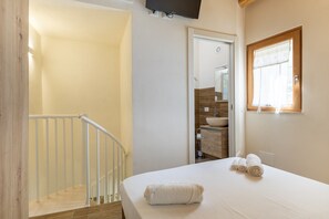 A bedroom with a bed, a bathroom with a sink, and a staircase.