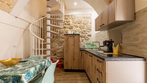 Eine Küche mit einer Holzausstattung, einer Steinwand und einer Wendeltreppe.