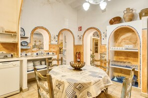 A dining area with a table set for two, surrounded by chairs, and a central decorative bowl.