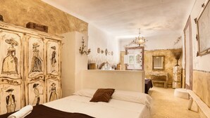 Ein Zimmer mit einem Bett, einem Schrank mit historischen Gemälden, einem Spiegel und einer Chandelier.