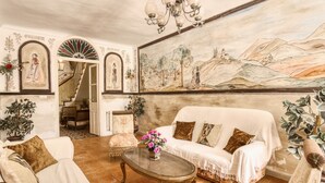 Ein Wohnzimmer mit einer Couch, Sesseln, einem Couchtisch und einem Wandbild.