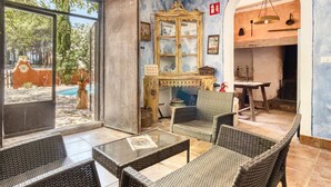 A room with wicker furniture, a glass table, a cabinet with glass doors, and a view of the outside.