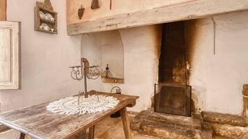 Una habitación rústica con una mesa de madera, una chimenea y una estantería con adornos.