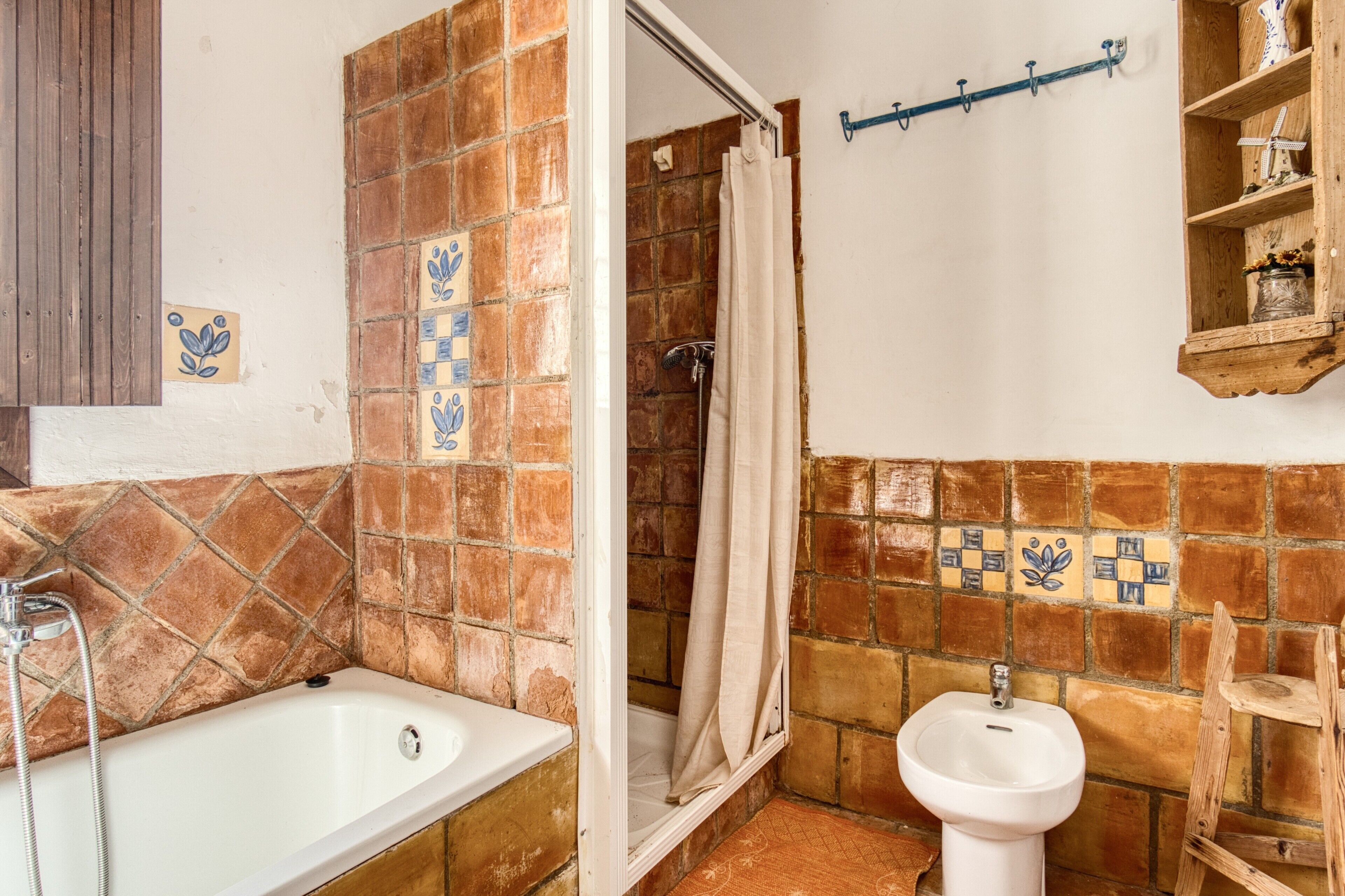 Un baño con bañera, ducha y lavamanos, con paredes de azulejos y estantes de madera.
