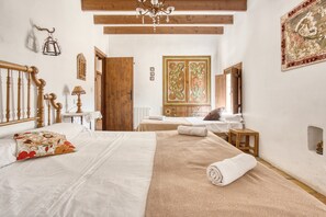 A bedroom with a wooden bed, a chandelier, a wooden door, and a large mirror. - Country House 'Madara' with Mountain Views, Private Pool and Wi-Fi (Monòver)