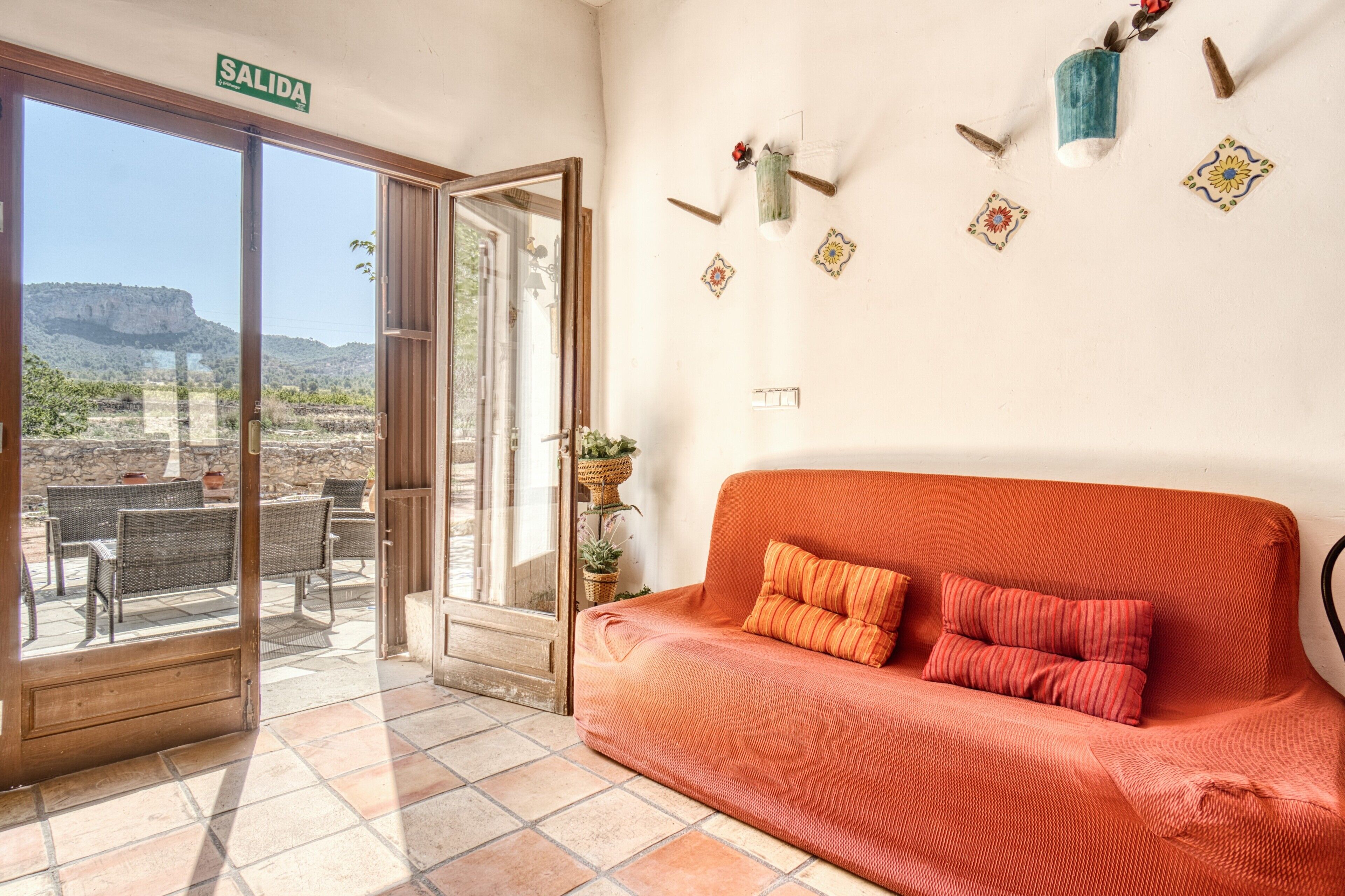 Una habitación con un sofá, una puerta con la leyenda 'SALIDA' y vistas al exterior.