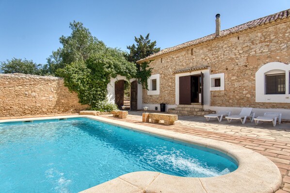 A stone building with a swimming pool, outdoor seating, and a stone wall. - Country House 'Madara' with Mountain Views, Private Pool and Wi-Fi (Monòver)