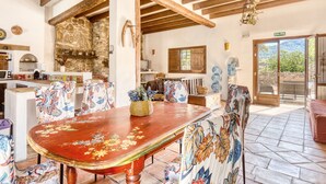A rustic dining area with a wooden table, patterned chairs, and a stone wall. - Country House 'Madara' with Mountain Views, Private Pool and Wi-Fi (Monòver)