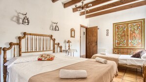 A bedroom with two beds, a wooden headboard, a chandelier, and a decorative door. - Country House 'Madara' with Mountain Views, Private Pool and Wi-Fi (Monòver)