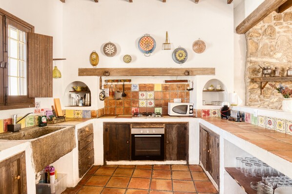 A kitchen with a stone wall, wooden cabinets, a built-in oven, and a tiled backsplash.
