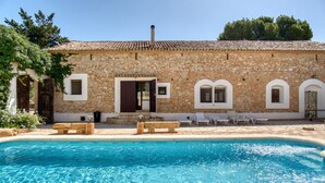 A stone building with a swimming pool, outdoor seating, and a clear blue sky. - Country House 'Madara' with Mountain Views, Private Pool and Wi-Fi (Monòver)