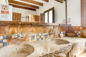 A rustic bathroom with two sinks, tiled walls, wooden beams, and a sign indicating no potable water. - Country House 'Madara' with Mountain Views, Private Pool and Wi-Fi (Monòver)