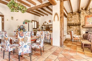 A rustic dining area with a wooden table and chairs, a stone wall, and a fireplace. - Country House 'Madara' with Mountain Views, Private Pool and Wi-Fi (Monòver)
