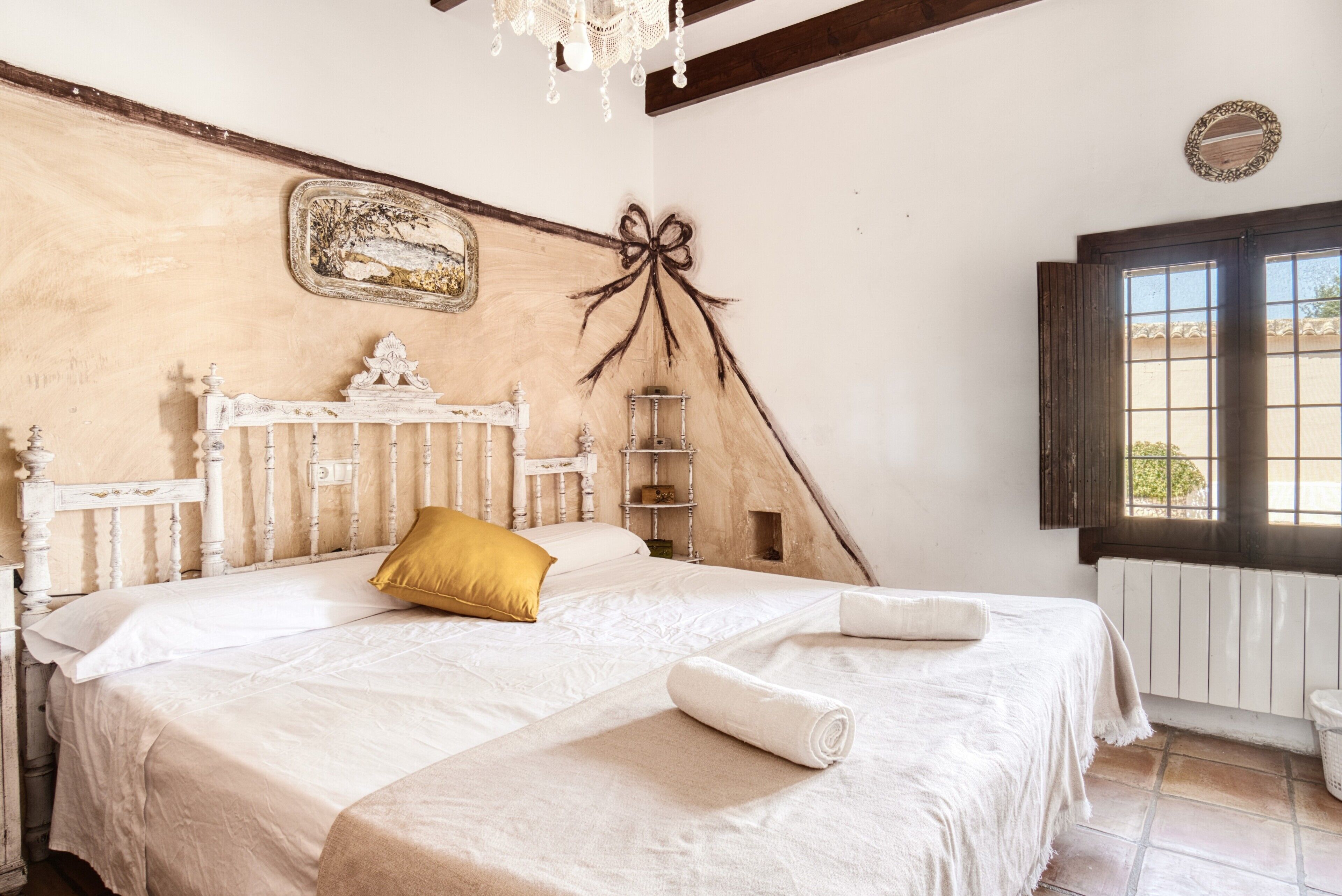 Un dormitorio con cama, candelabro, ventana y estante en la pared.
