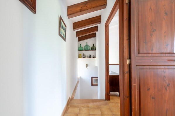 A hallway with wooden beams, a tiled floor, and a door with a wooden panel.