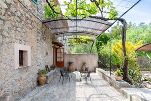 A stone building with a covered patio, outdoor seating, and potted plants. - Holiday Home 'Ca'n Repic' with Mountain View, Private Terrace and Wi-Fi (Illes Balears)
