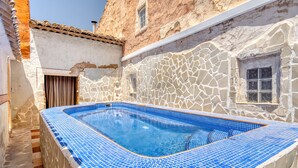 Une piscine aux carreaux de mosaïque bleus, un mur en pierre et une fenêtre.