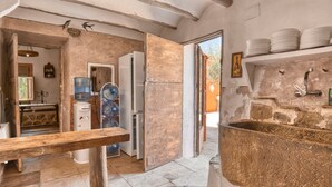 Une cuisine rustique avec un évier en pierre, des poutres en bois et un distributeur d’eau.