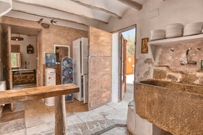 Une cuisine rustique avec un évier en pierre, des poutres en bois et un distributeur d’eau.
