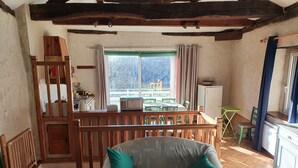 Ein Zimmer mit einer hölzernen Sitzbank, einem Tisch mit Stühlen, einem Fenster mit Vorhängen und einer Küchenzeile.