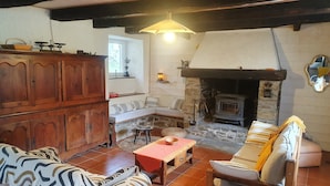 Un salón acogedor con chimenea de piedra, muebles de madera y un banco.