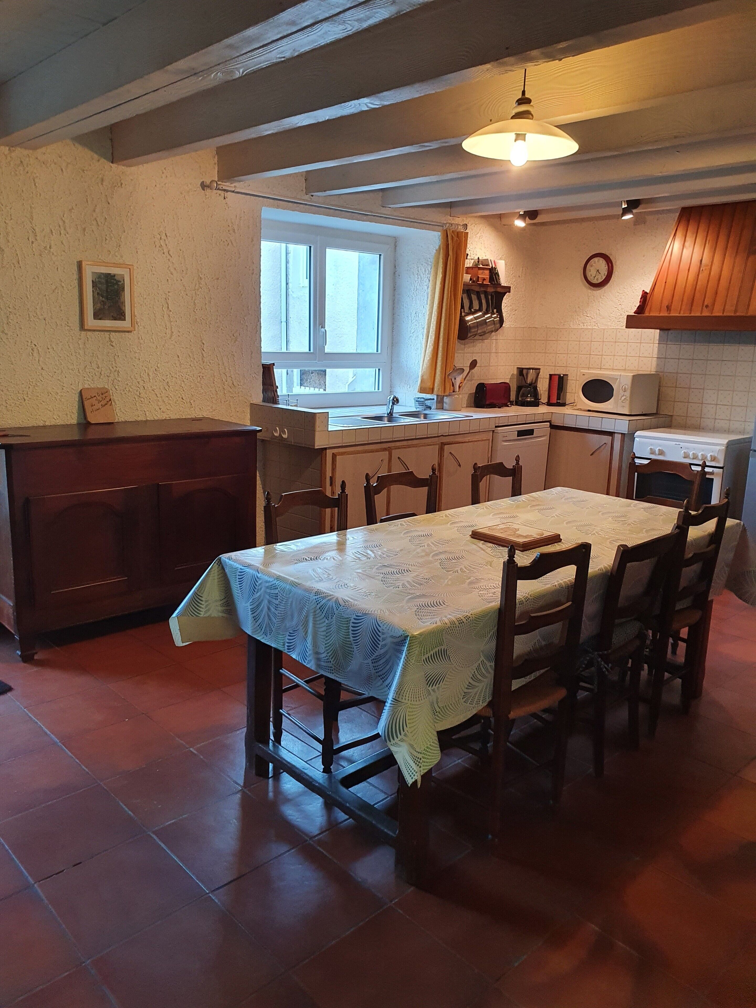 A kitchen with a dining table, chairs, a window, and basic appliances.