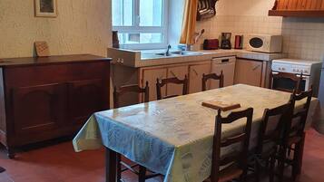 A kitchen with a dining table, chairs, a window, and basic appliances.