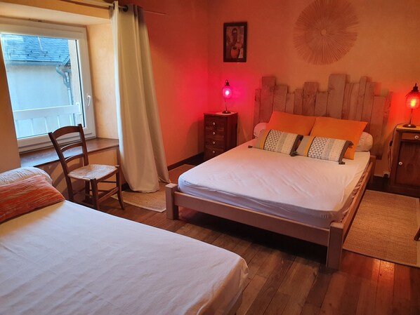 A bedroom with two beds, a chair, a dresser, and a window with curtains.